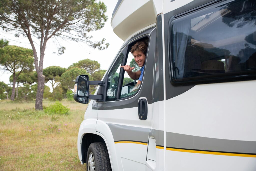 Smiling man driving a camper van through scenic countryside in Portugal, enjoying the adventure.